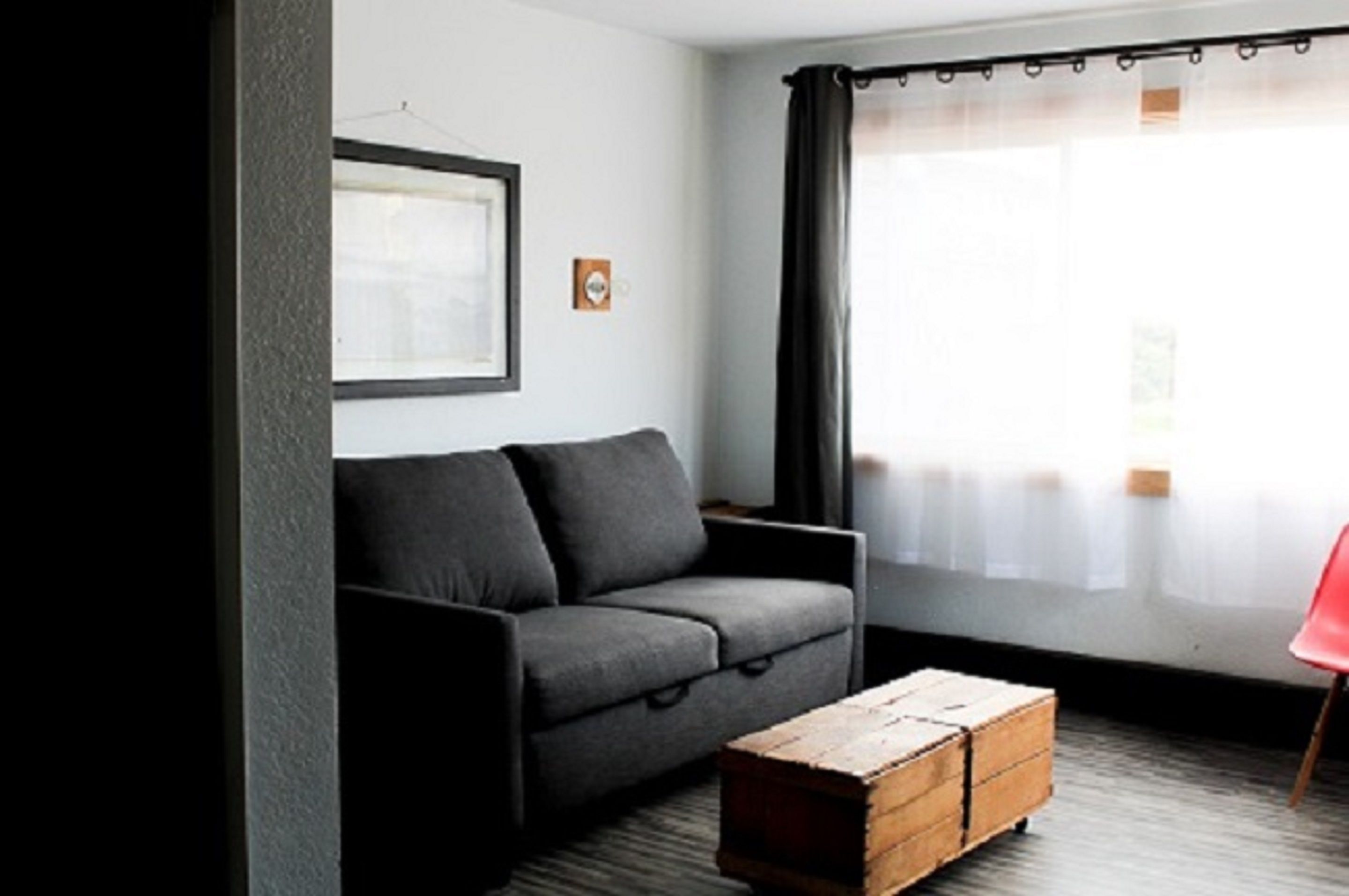 Una sala de estar moderna con un sofá gris, una mesa de centro de madera y una silla roja.