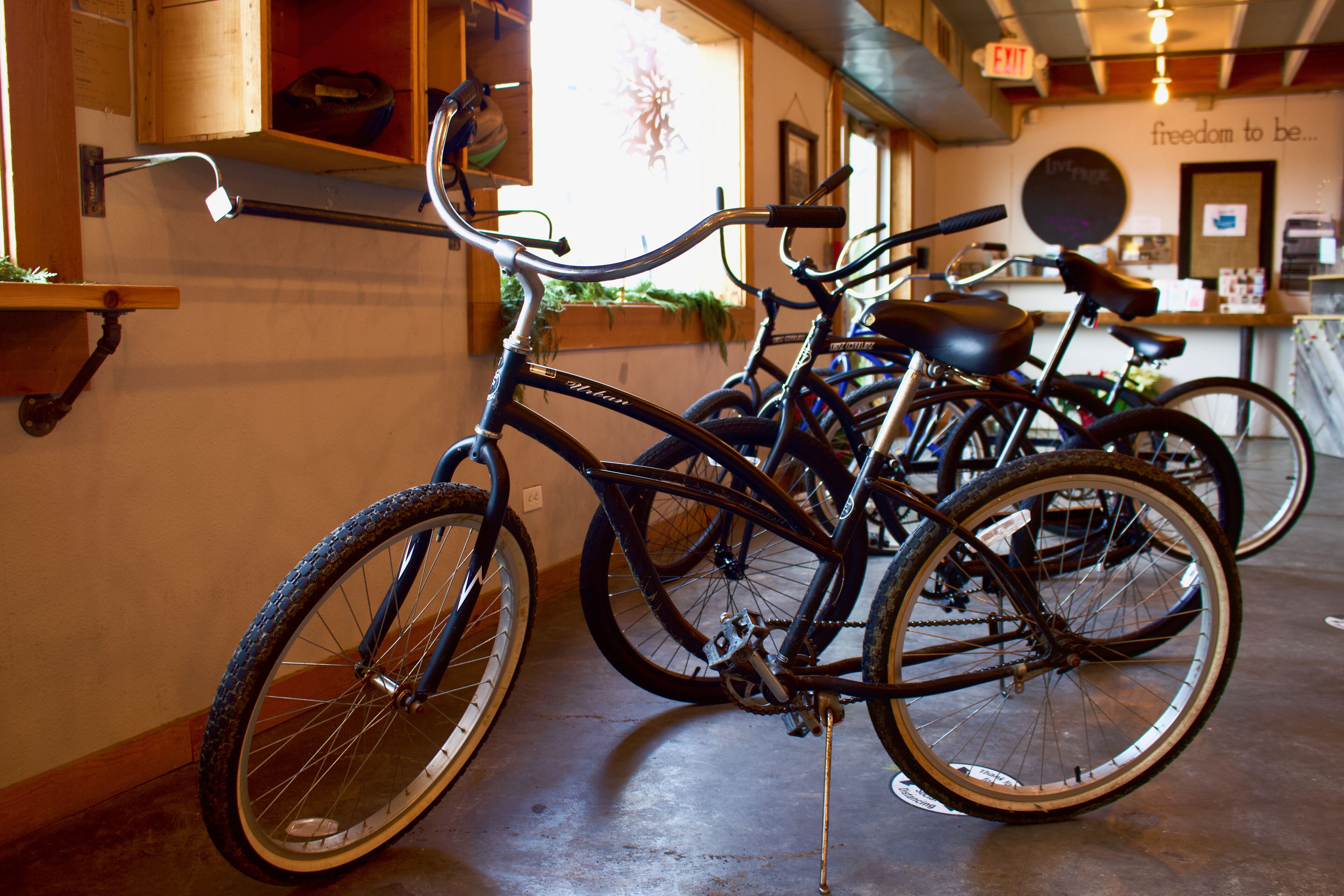 Bicycles parked indoors with a wall-mounted rack and a sign indicating an exit.