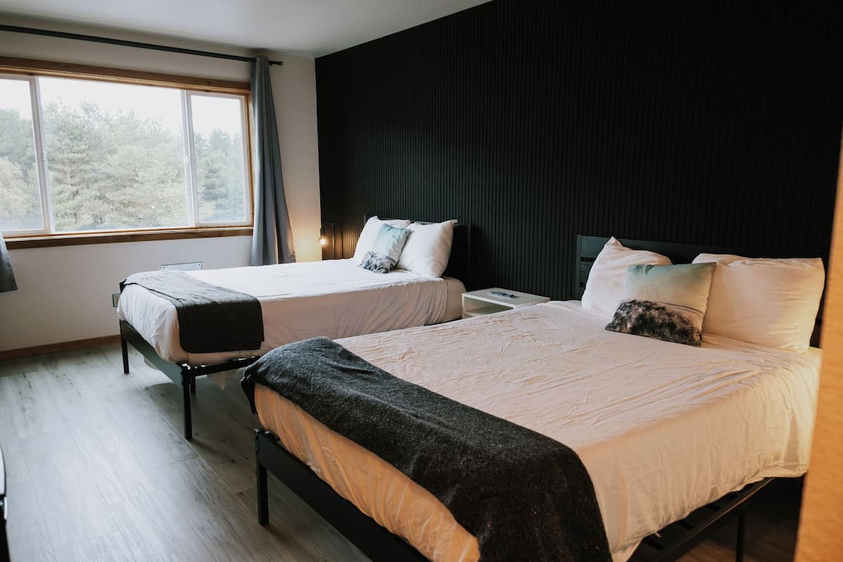Ein Hotelzimmer mit zwei Betten, einem großen Fenster und einer dunklen Wand.