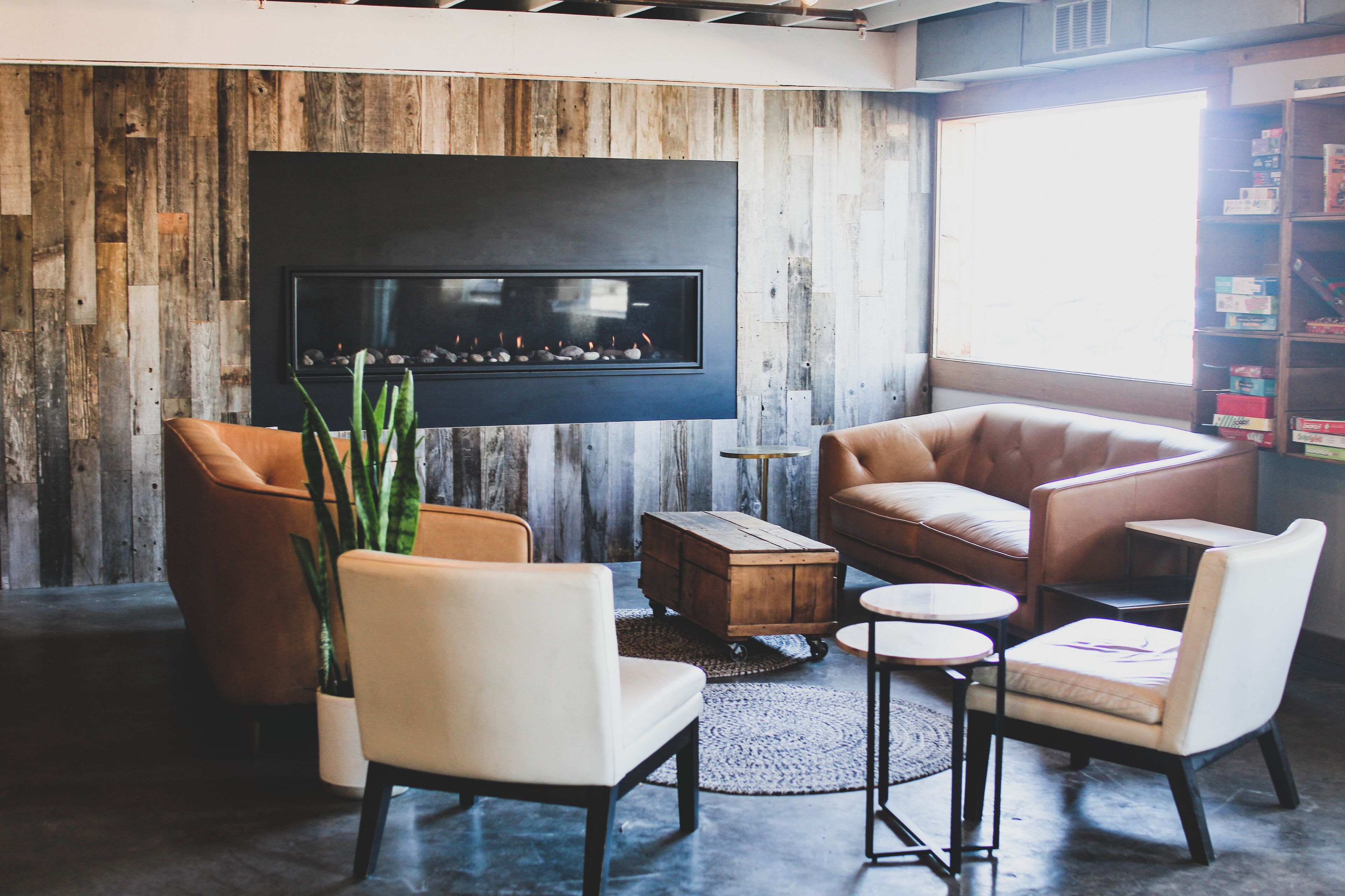 Una sala de estar moderna con chimenea, sofás de cuero, una mesa de centro y una estantería.