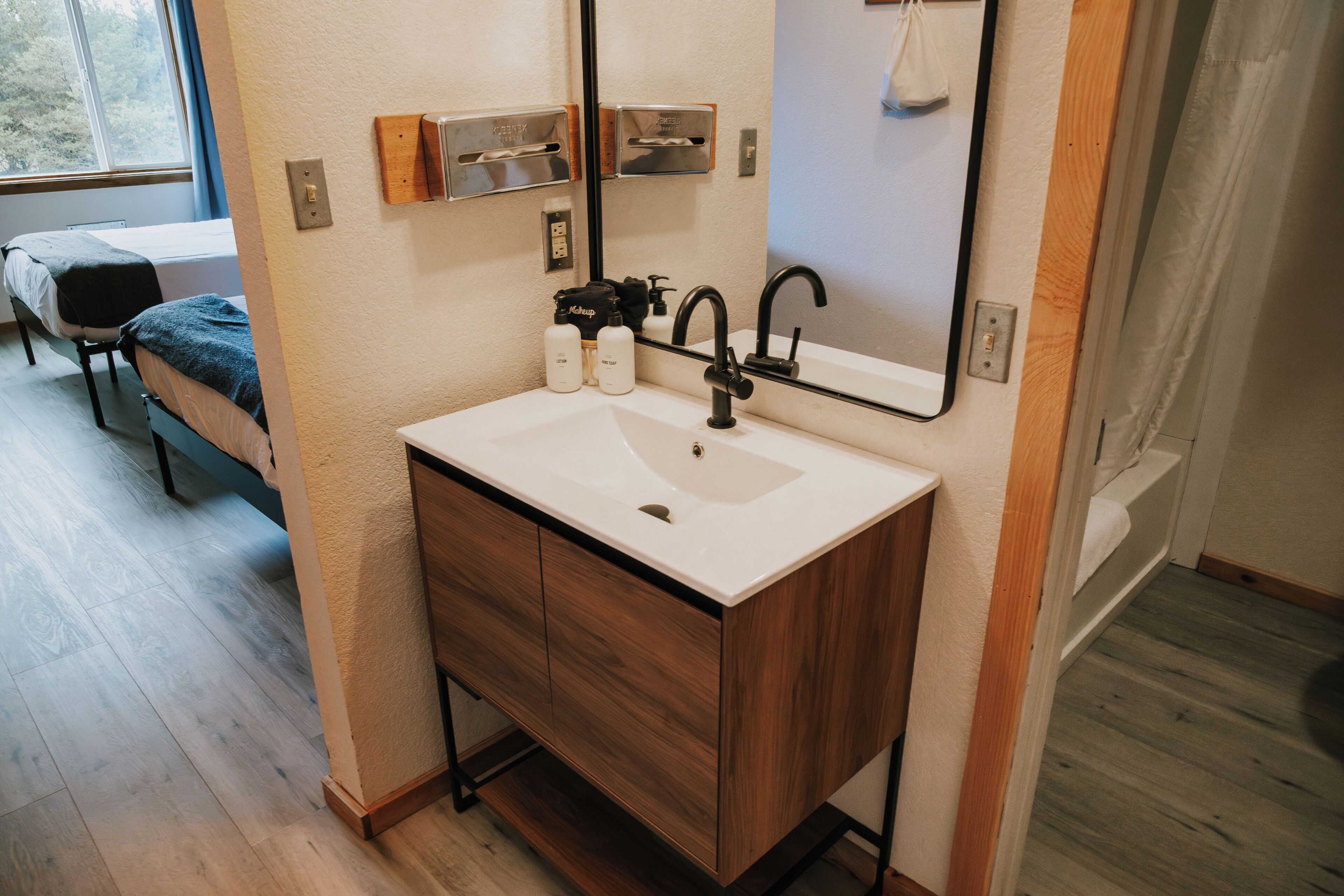A modern bathroom with a white sink, wooden vanity, and a mirror.