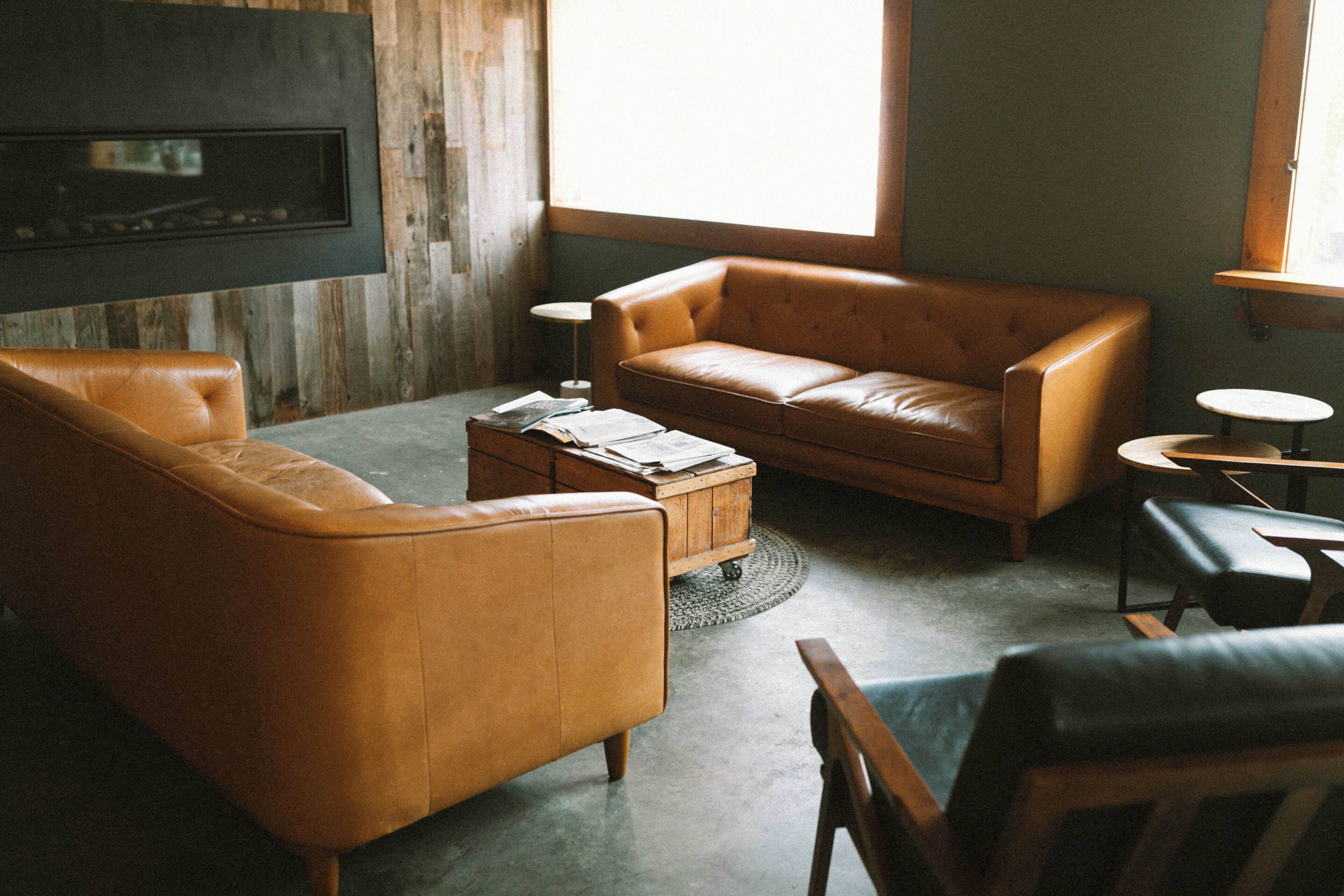 A cozy living room with a brown leather sofa, a coffee table, and a fireplace.