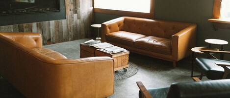 A cozy living room with a brown leather sofa, a coffee table, and a fireplace.
