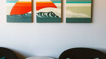 Een kamer met een ronde tafel, twee stoelen en drie schilderijen aan de muur.