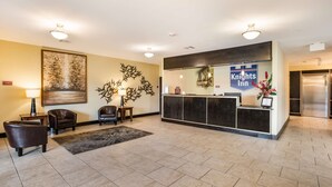 A hotel lobby with a reception desk, leather chairs, a large abstract painting, and a reception area with a Knights Inn sign. - Knights Inn Bunkie (Bunkie)