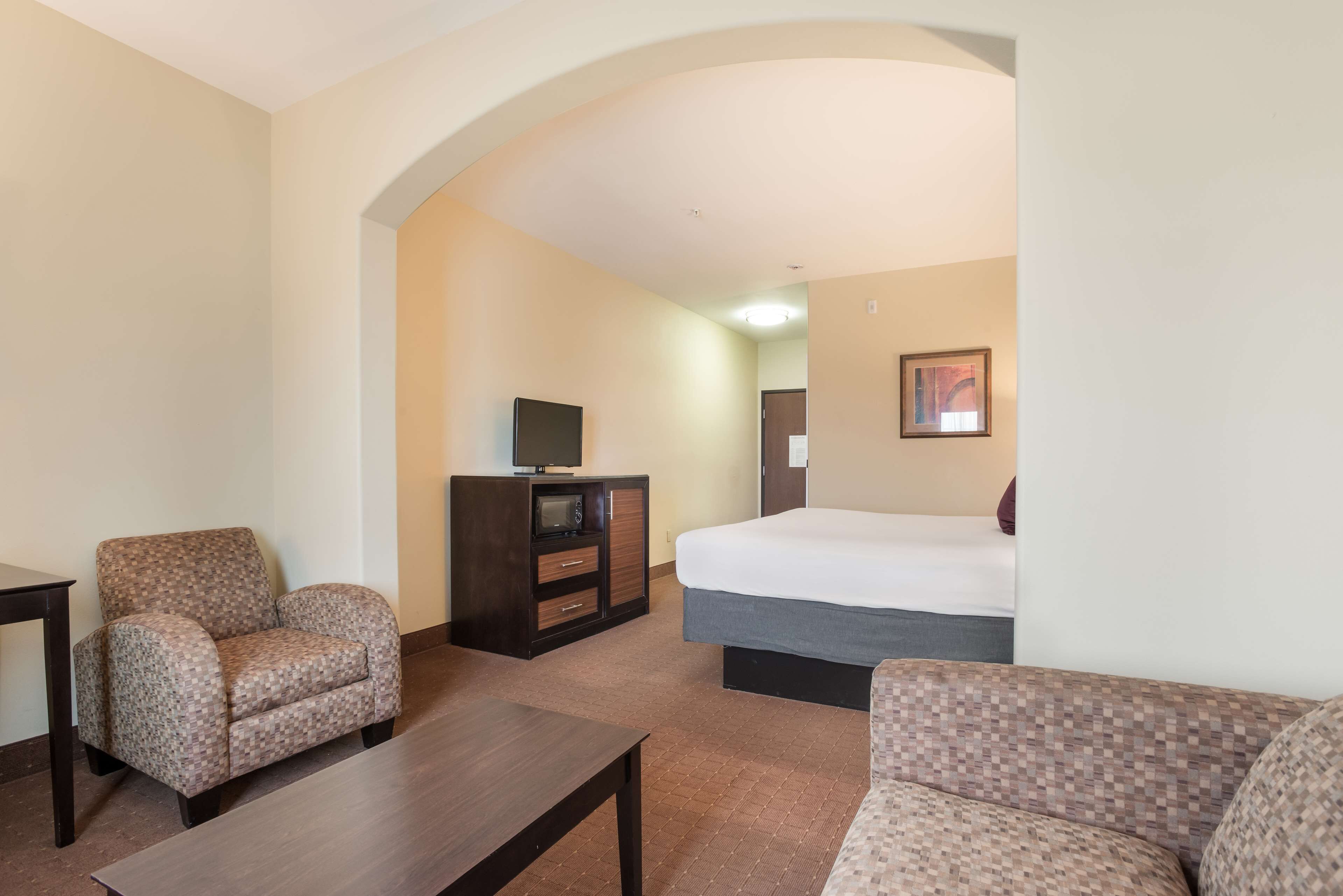 A hotel room with a bed, a sofa, a chair, a TV, and a desk.