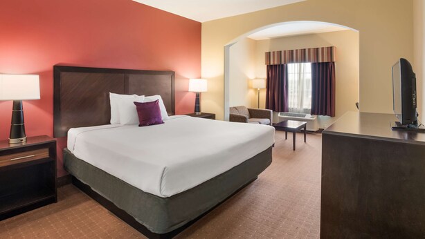 A hotel room with a large bed, a desk, a chair, and a TV. - Knights Inn Bunkie (Bunkie)