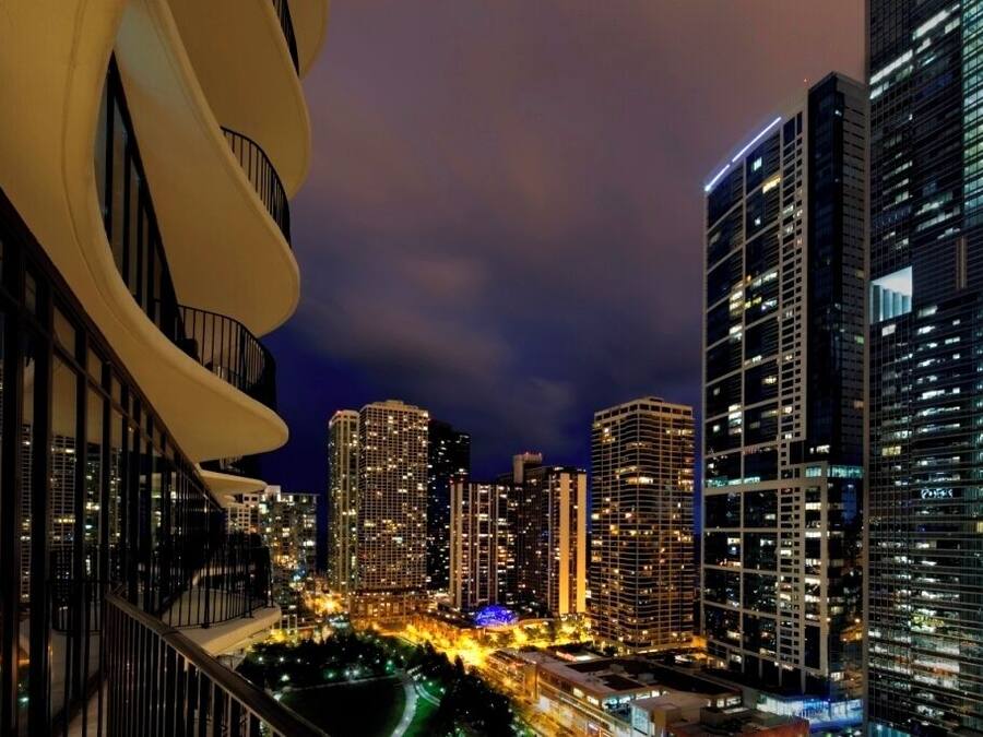 A nighttime cityscape with high-rise buildings, a curved architectural feature, and a well-lit urban area.