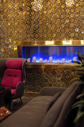 A room with a patterned wall, a red chair, a blue-lit water feature, and a candle display. - Radisson Blu Aqua Hotel Chicago (Chicago)