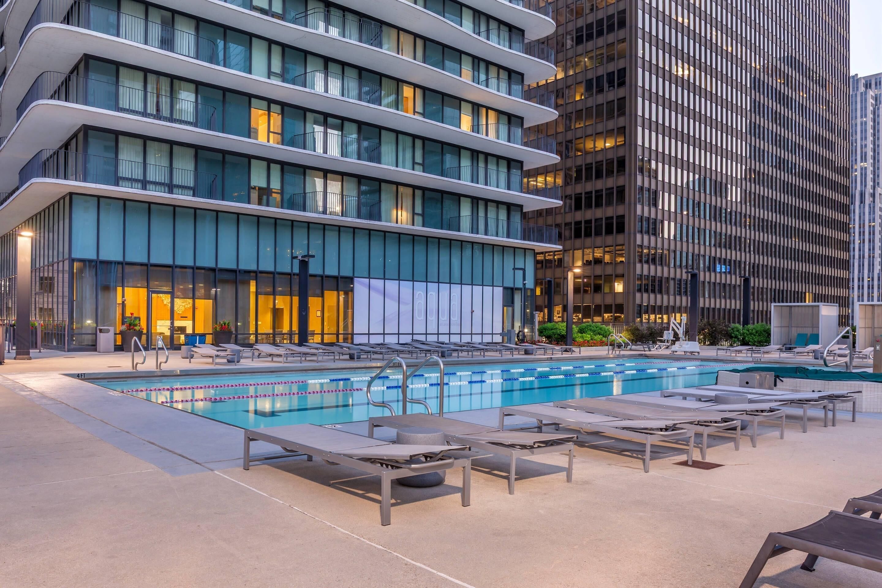 Un hotel moderno con piscina, tumbonas y vistas a la ciudad.