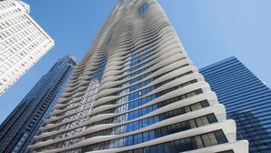 A modern skyscraper with a unique wavy facade, surrounded by other high-rise buildings.