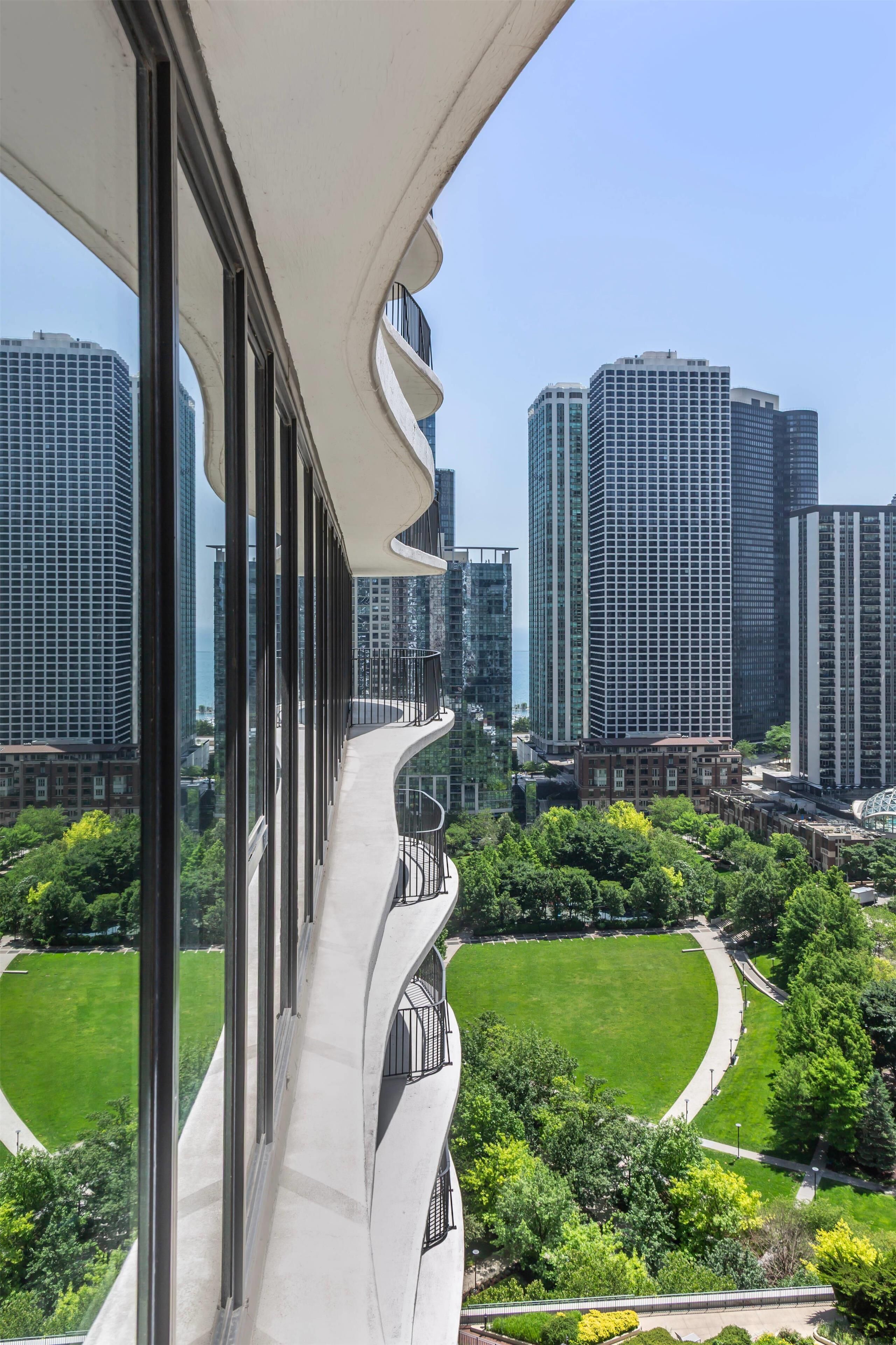 A modern building with a curved balcony overlooking a cityscape and a park.