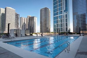 A swimming pool with lane dividers, surrounded by lounge chairs and a cityscape with tall buildings in the background. - Radisson Blu Aqua Hotel Chicago (Chicago)