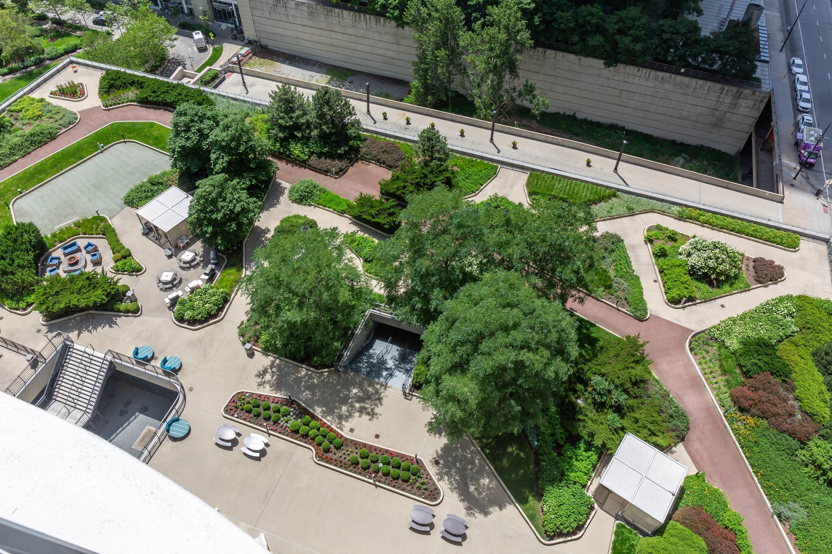 An aerial view of a landscaped courtyard with pathways, seating areas, and a central water feature.