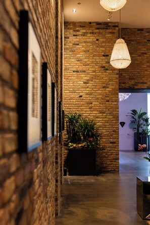 A corridor with a brick wall, hanging wicker light fixture, and potted plants. - Radisson Blu Aqua Hotel Chicago (Chicago)