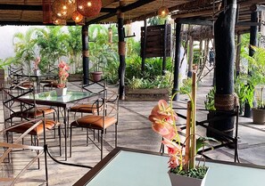 An outdoor dining area with tables and chairs, surrounded by potted plants and a thatched roof structure. - Eurobuilding Hotel Plaza Guayana (Ciudad Guayana)