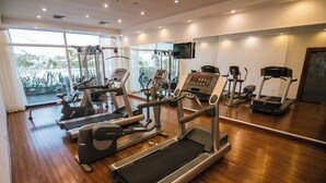 A gym with various cardio machines, a television, and large windows. - Eurobuilding Hotel Plaza Guayana (Ciudad Guayana)