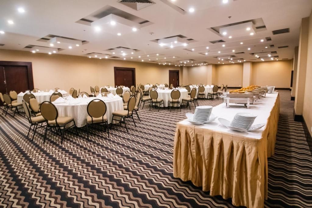 Un salón de conferencias con mesas redondas, sillas y una mesa de bufé.