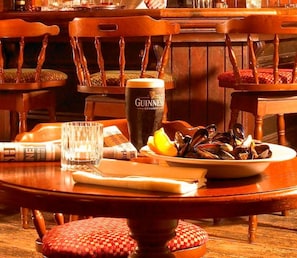 A dining table with a plate of mussels, a glass of Guinness beer, and a newspaper. - Glengarriff Park Hotel (Glengarriff)