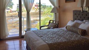 Une chambre d’hôtel avec un lit, une chaise, un tableau au mur et une vue sur l’extérieur.