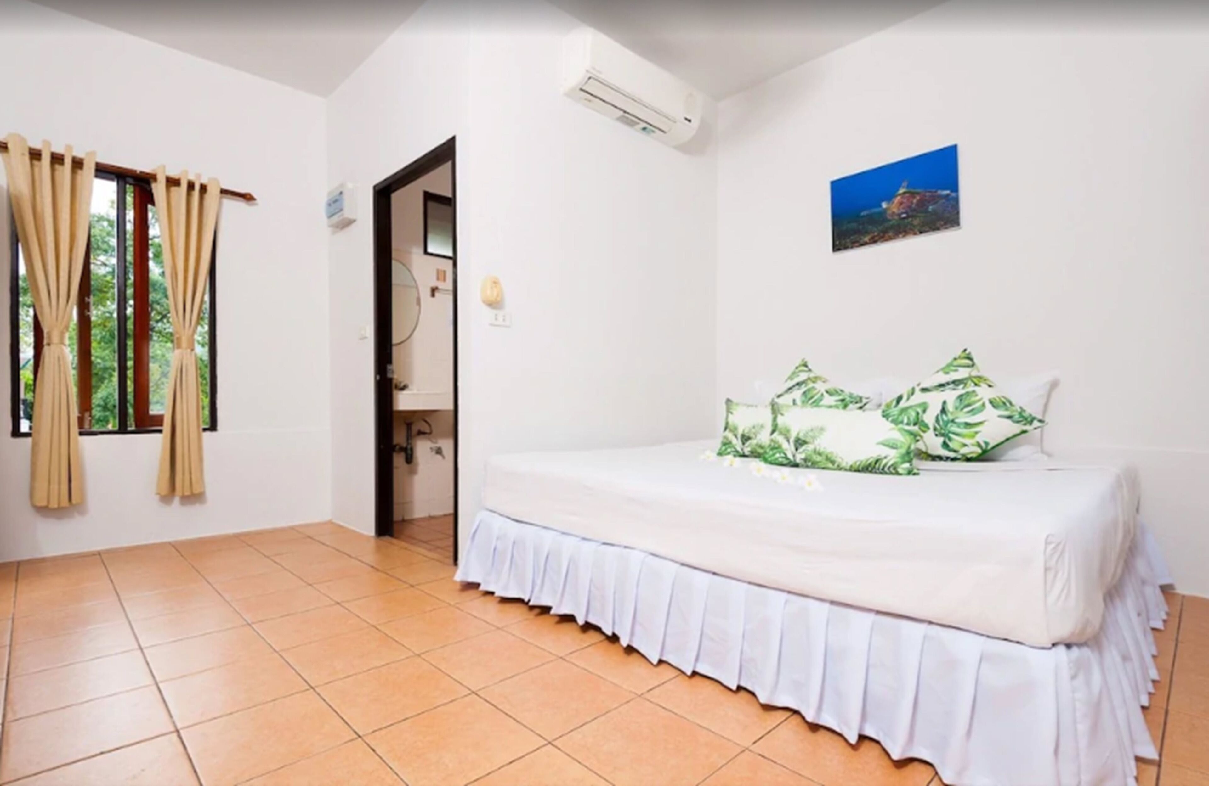 Un dormitorio con cama, cortinas, aire acondicionado y un cuadro en la pared.