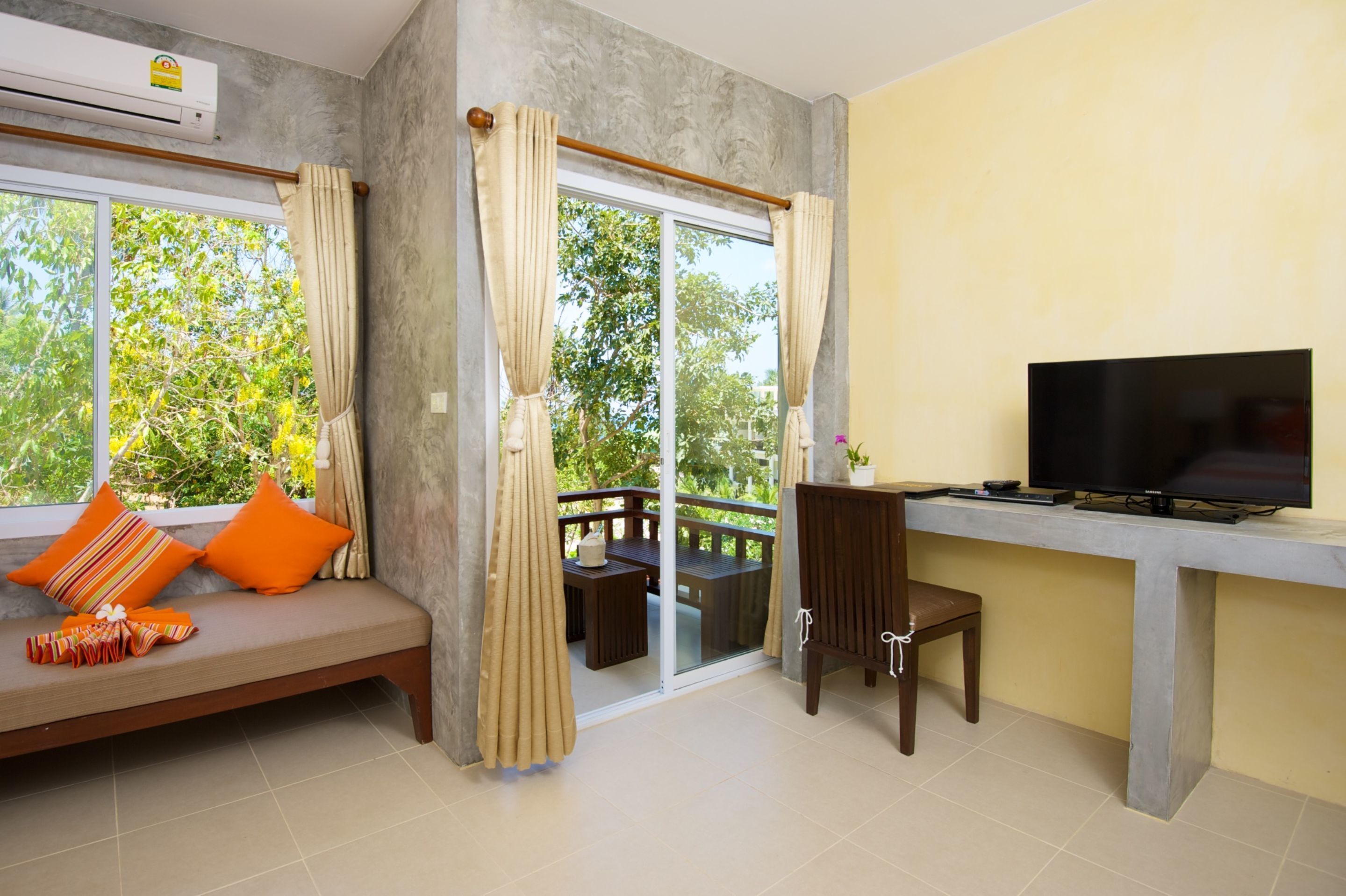 A room with a sofa, a TV, a balcony, and a dining area.