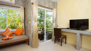 A room with a sofa, a TV, a balcony, and a dining area.