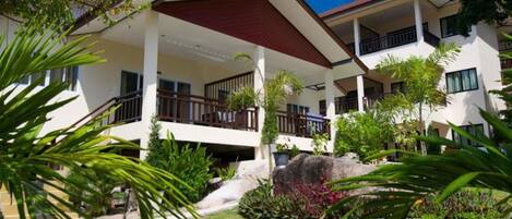 A multi-story hotel with a covered outdoor area, surrounded by lush greenery and palm trees.