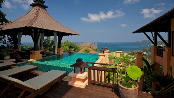 Un espace aménagé au bord de la piscine, avec des chaises longues, un gazebo et une vue sur l’océan.