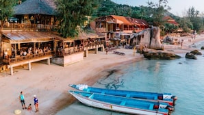 Une zone côtière avec une plage, une jetée en bois et un bateau amarré sur le rivage.
