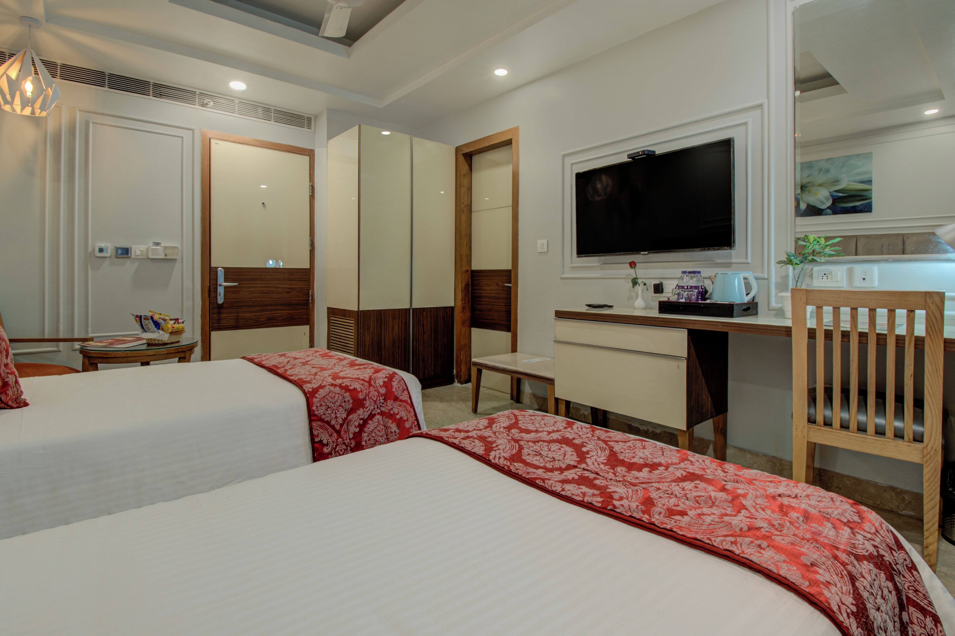 A hotel room with two beds, a desk, a television, and a chair.