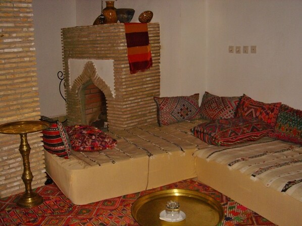 A cozy living room with a sofa, patterned cushions, a small table, and a decorative wall.