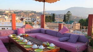 A terrace with a sofa set, dining table, and a view of a cityscape.