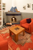 Uma sala de estar com lareira estampada, um sofá vermelho e uma mesa de centro.