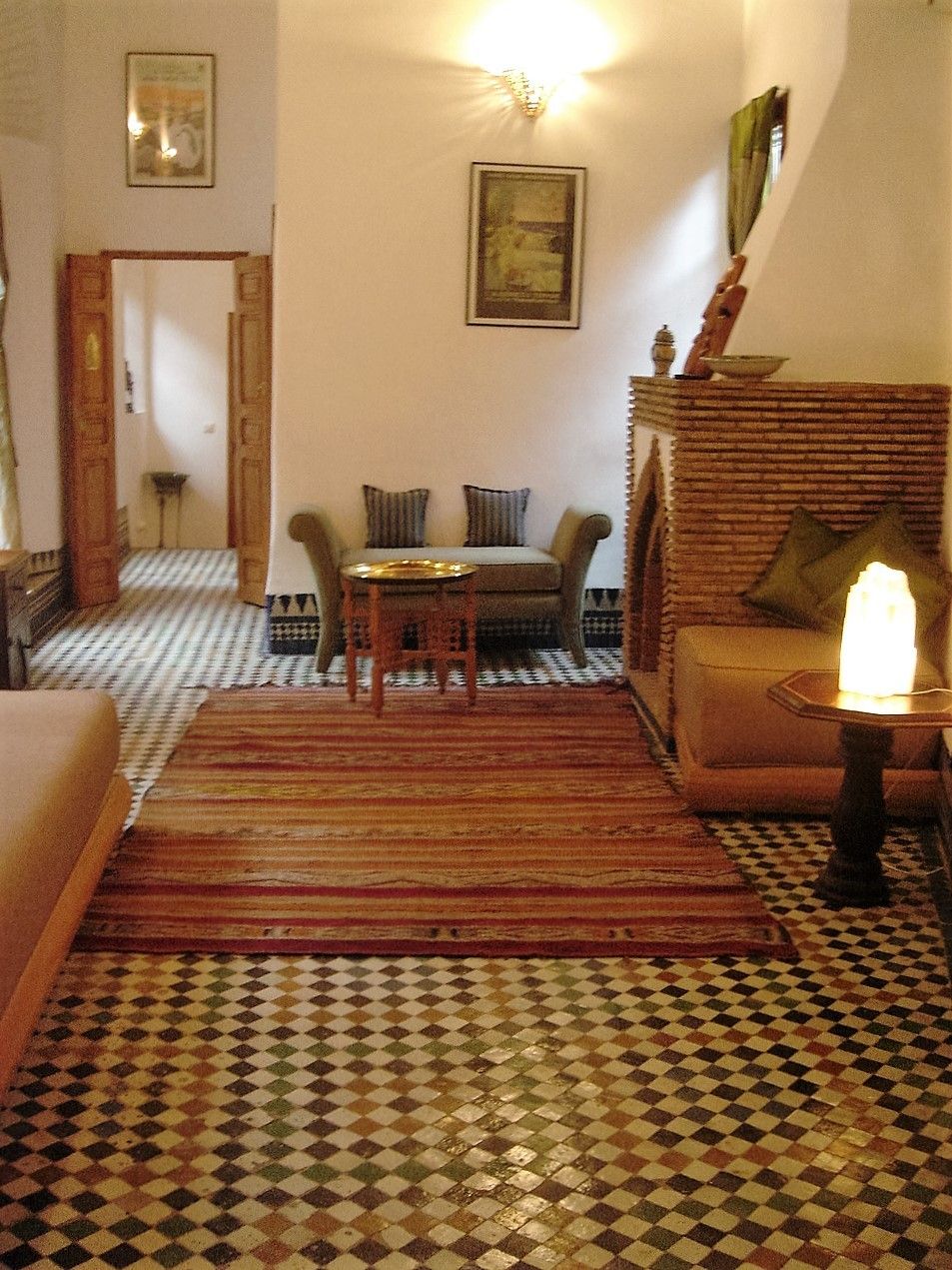 Una habitación con piso a cuadros, un sofá, una mesa y una lámpara.