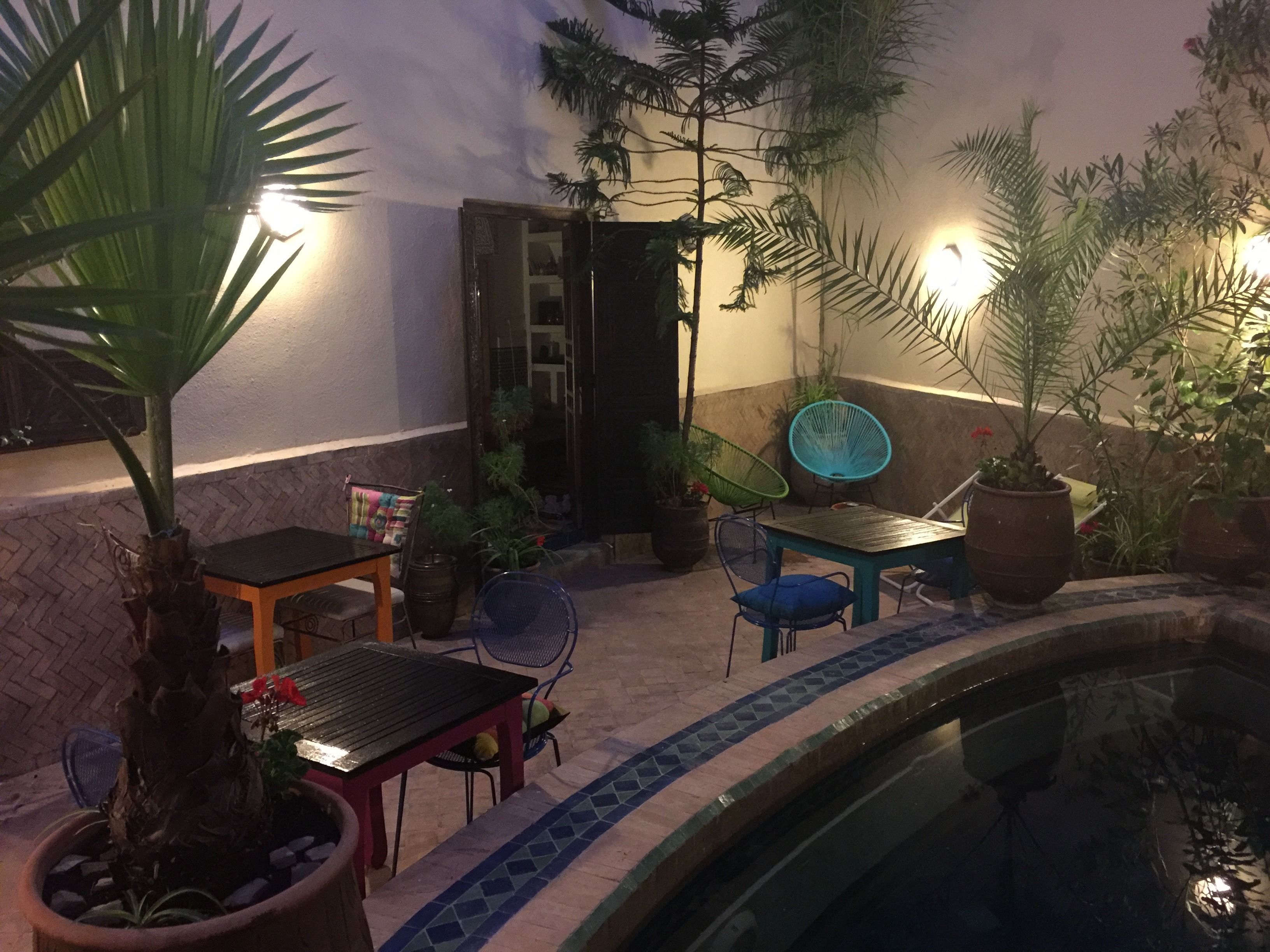 Un patio al aire libre con piscina, zona de estar y plantas en macetas.