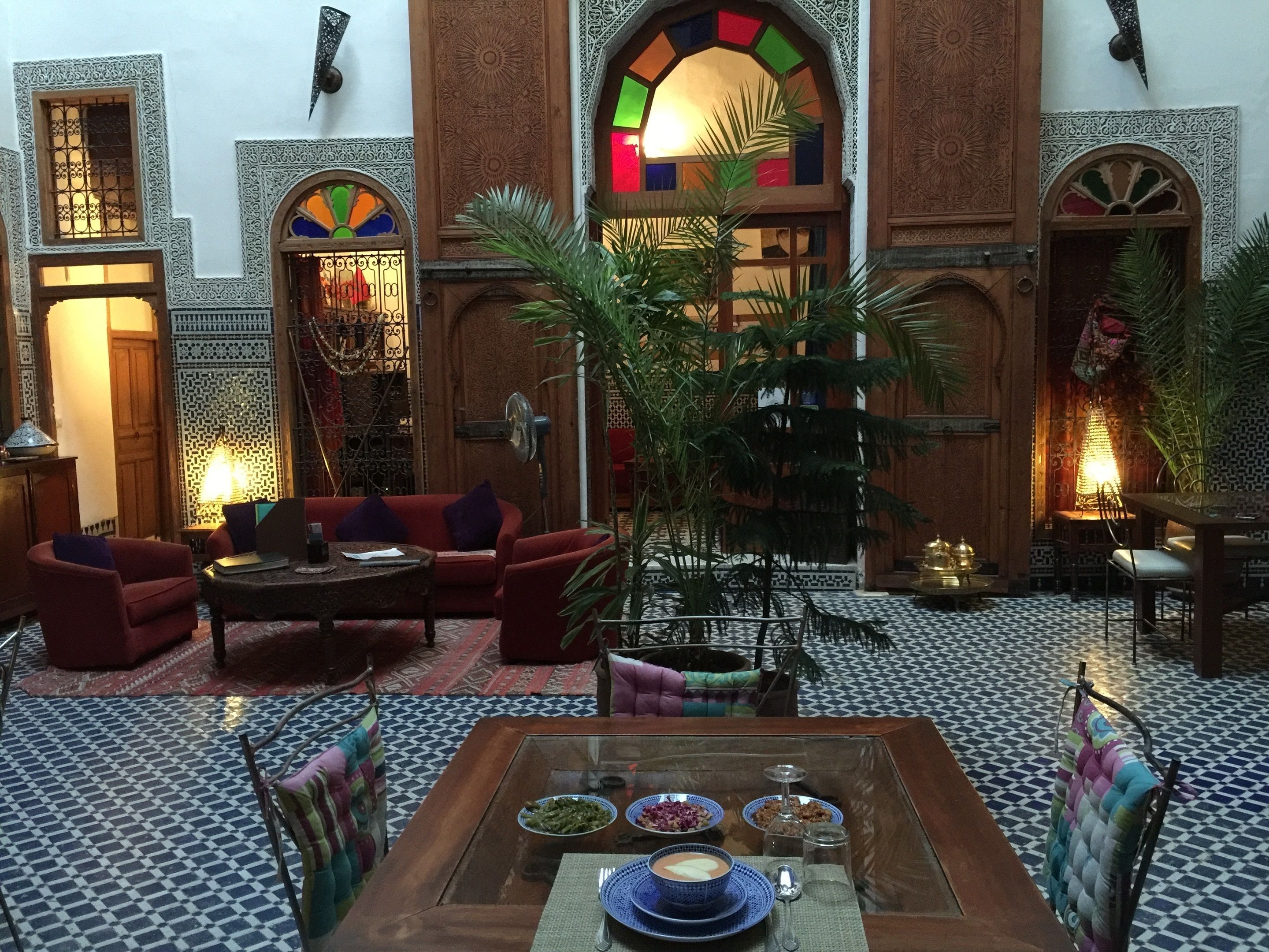 A traditional Moroccan interior with a seating area, a dining table, and decorative elements.