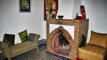 A room with a checkered floor, a brick fireplace, a sofa, and a poster on the wall.
