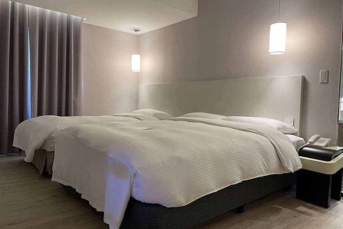 Une chambre d’hôtel moderne avec un grand lit, une table de chevet avec un téléphone et une tête de lit.