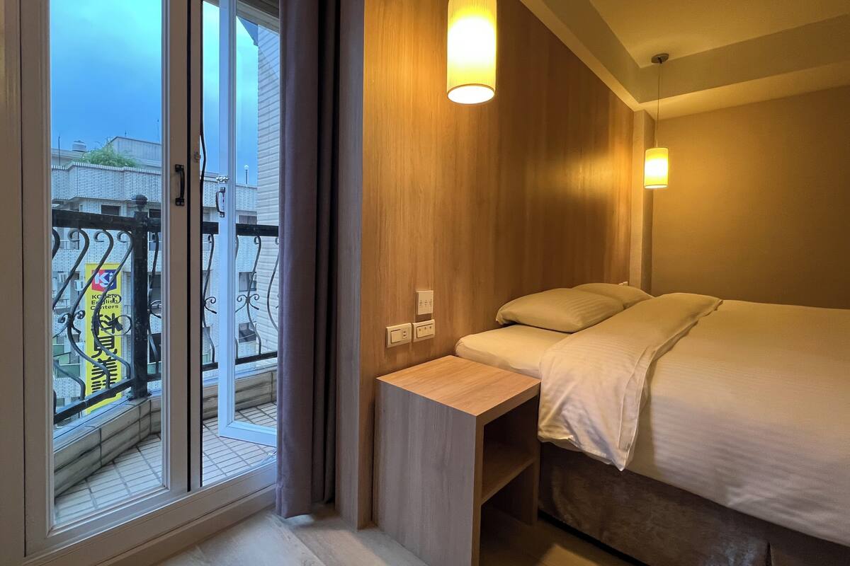 Une chambre d’hôtel avec un lit, une table de chevet et une vue sur le balcon extérieur.