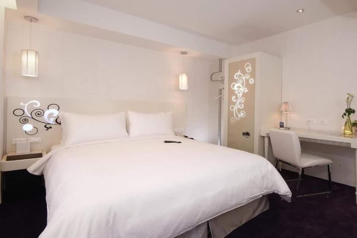 Une chambre d’hôtel avec un grand lit, un bureau et un miroir.