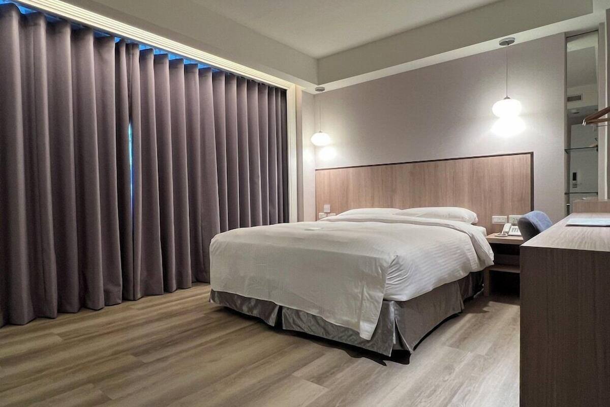 Une chambre d’hôtel avec un grand lit, un bureau et un miroir.