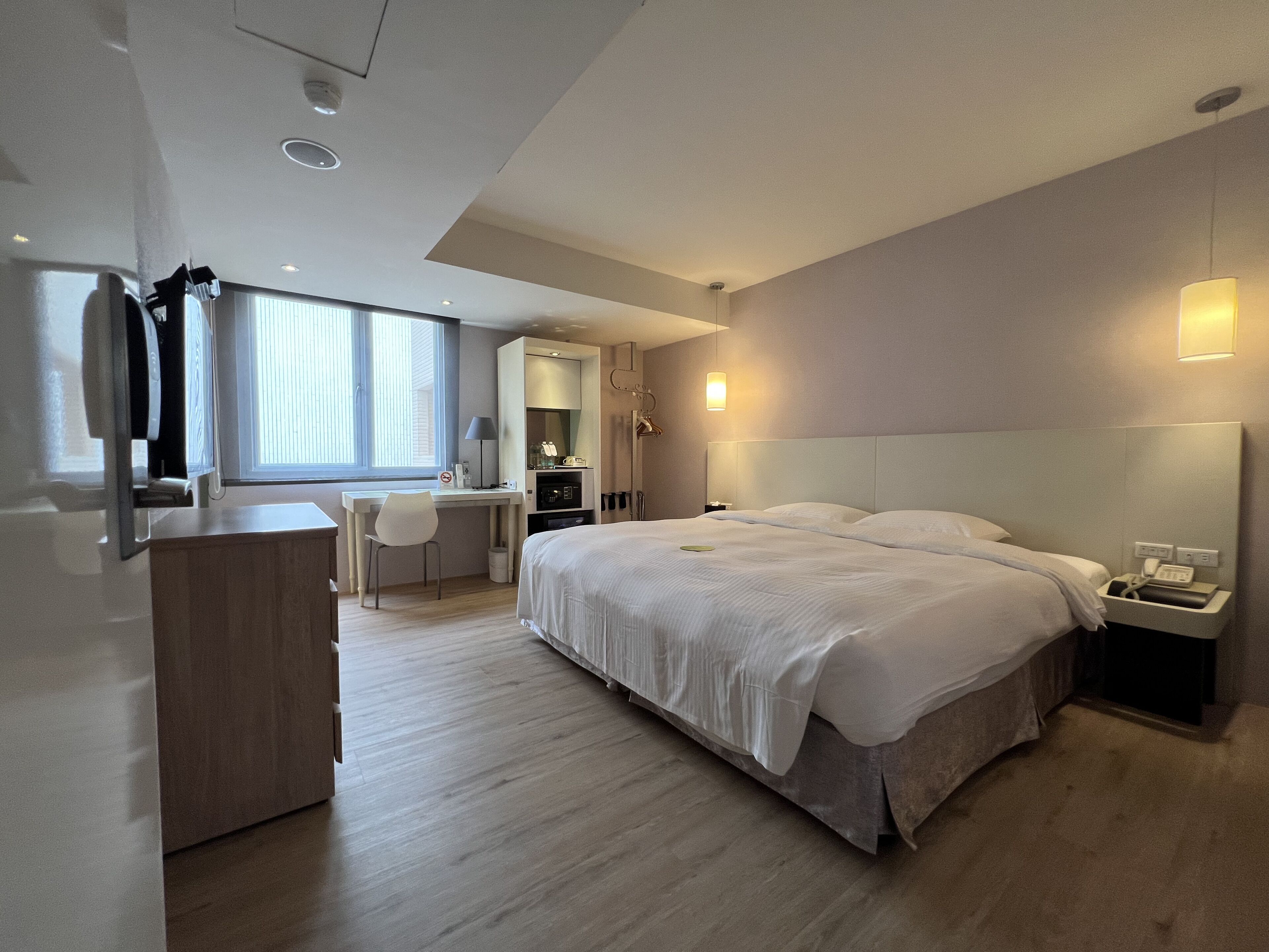 A modern hotel room with a large bed, a desk, and a chair.