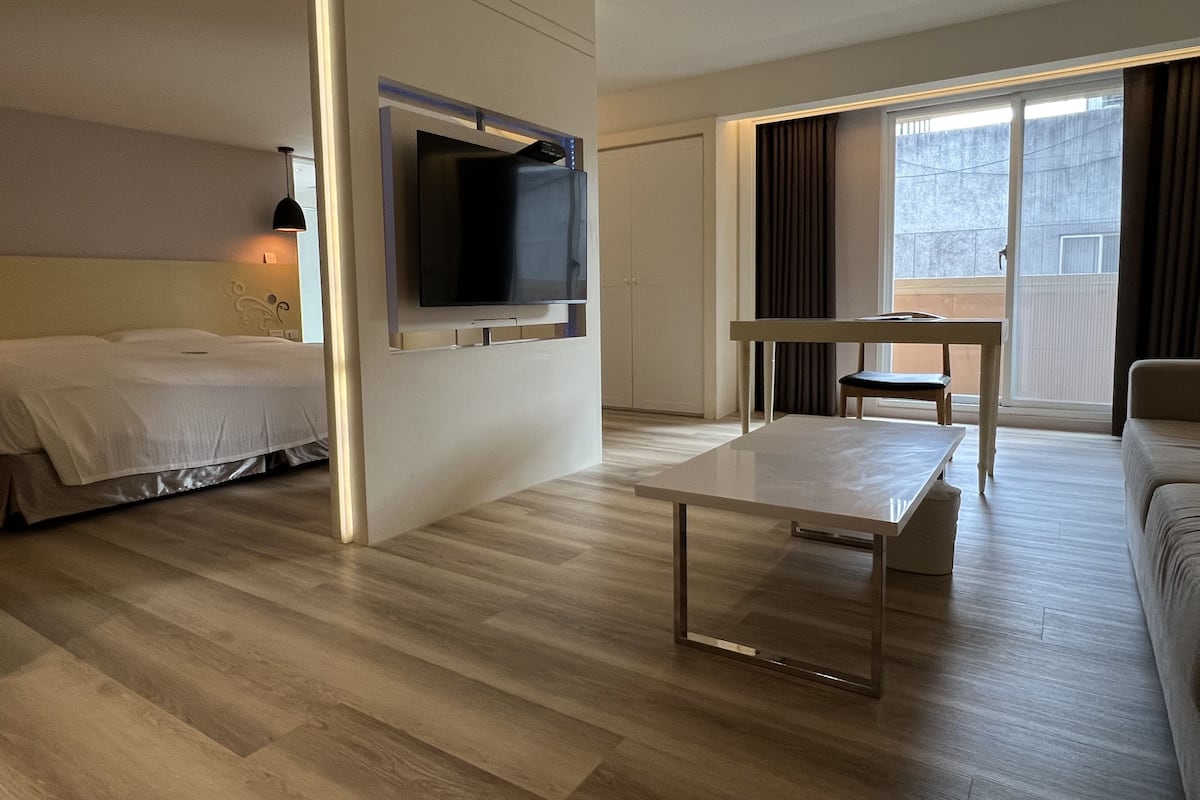 Une chambre d’hôtel comprenant un lit, un téléviseur fixé au mur, une table à manger et un canapé.