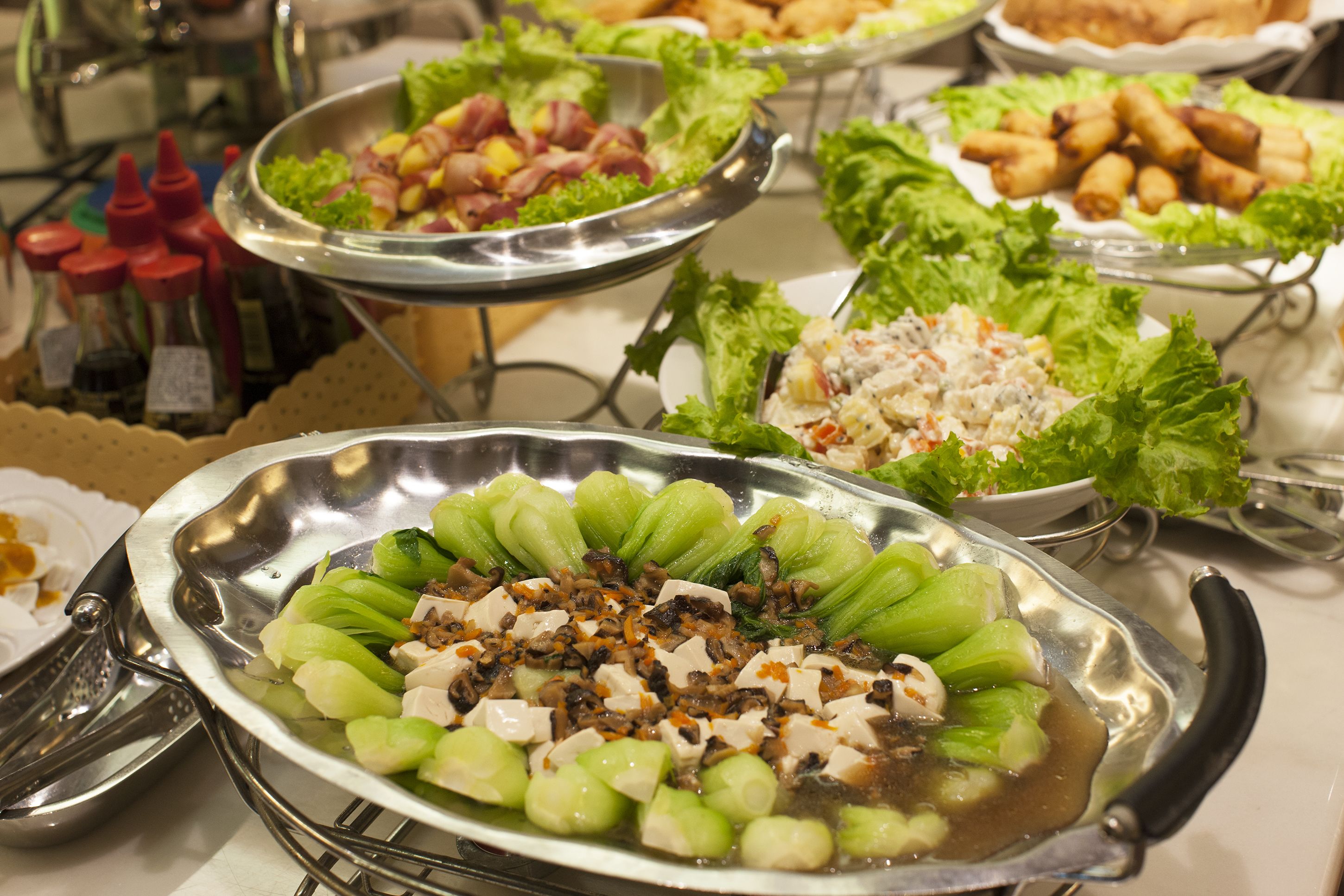 Een buffet met diverse gerechten, waaronder salades, vlees en groenten.