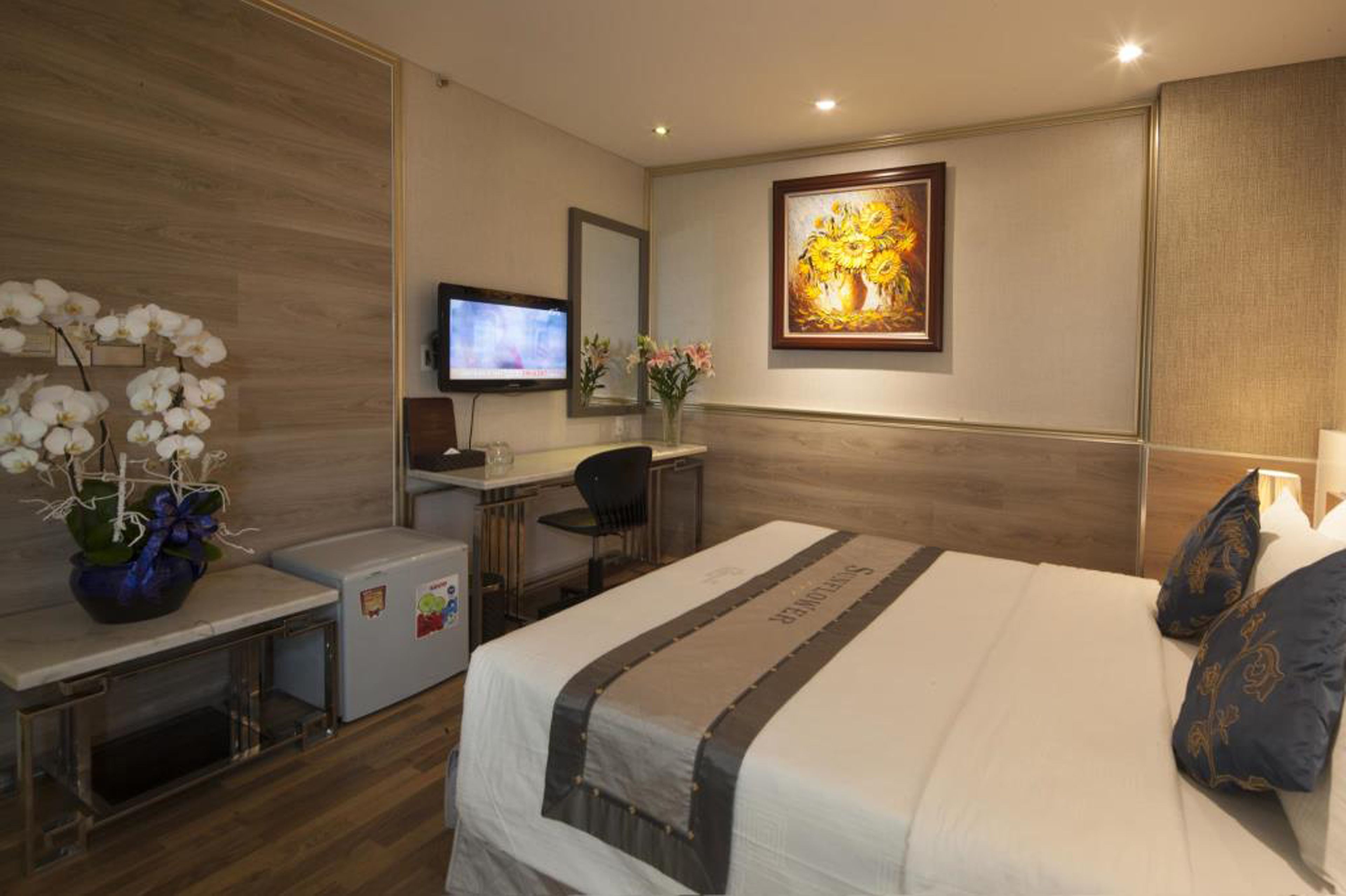 A hotel room with a bed, desk, and television.