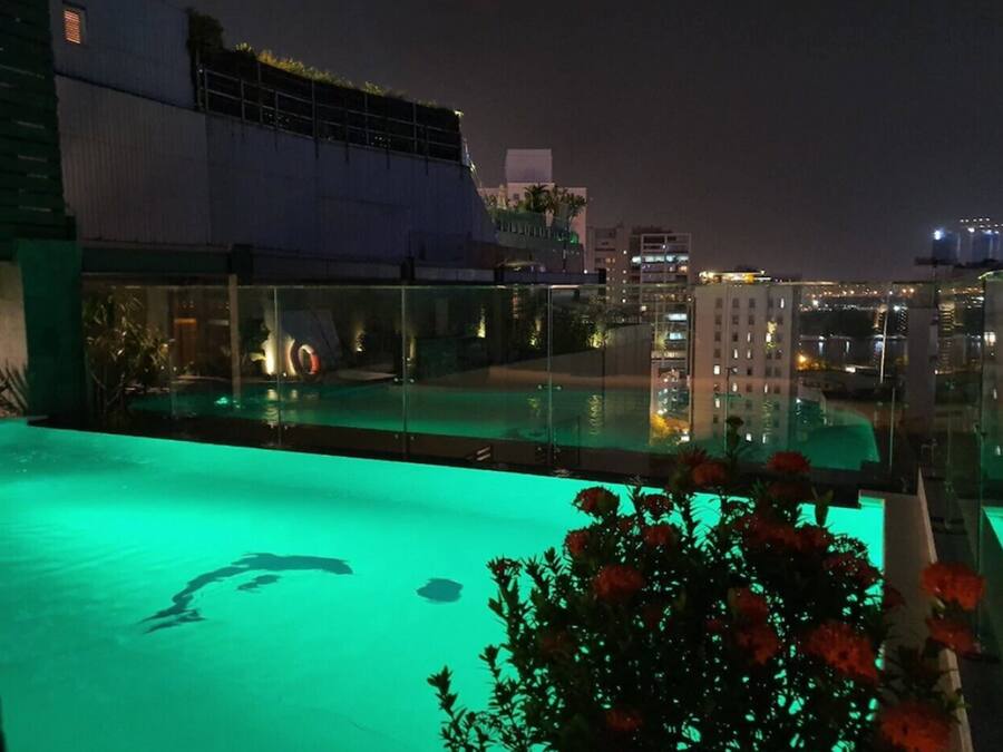Uma piscina no terraço com barreira de vidro, cercada por vegetação e flores.