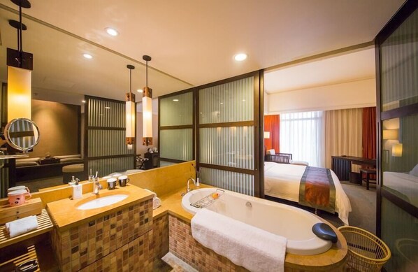 A modern hotel bathroom with a large bathtub, a separate sink area, and a mirror.