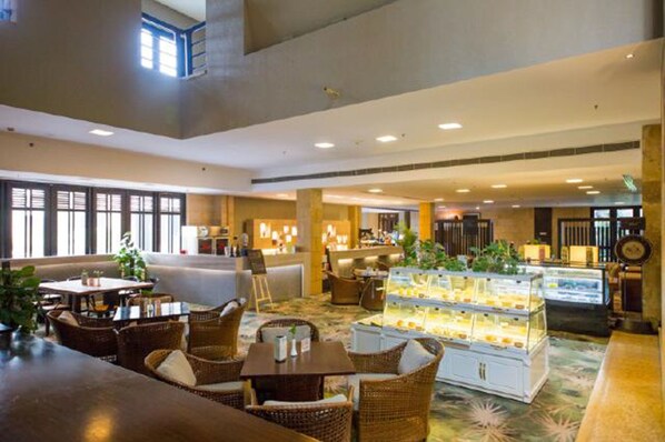 A spacious hotel lobby with a seating area, a counter, and a display case.