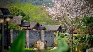 A traditional-style building with a stone wall and multiple wooden structures with sloped roofs. - NARADA Resort & Spa Liangzhu (Hangzhou)